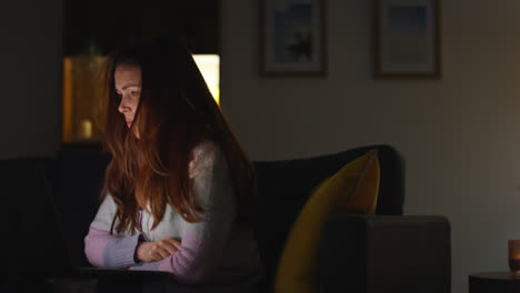 Anxious-Woman-Sitting-On-Sofa-At-Home-At-Night-Looking-At-Laptop-Concerned-About-Social-Media-Or-Bad-News-10